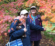 two smiling participants in front of a maple tree