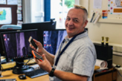 Photo of Jason Spinney smiling and surrounded by tech devices
