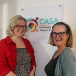 Photo of Pippa Baker-Walsh and Emma Royer standing next to a CASA sign.