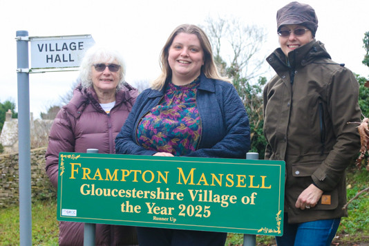 Village of the Year sign, with Parish Clerk Babs Maloney, GRCC Community Development Officer Sabrina Dixon, and award-winning village volunteer Lucy Cameron-Davies.