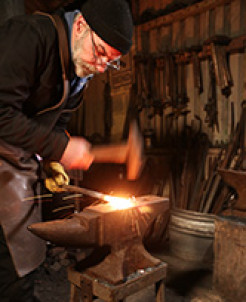 Photo of Adrian Leljack hammering red hot metal on an anvil