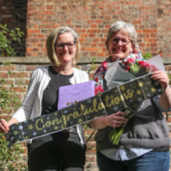 Emma Royer and Pippa Baker-Walsh pictured holding a "Congratulations" banner.