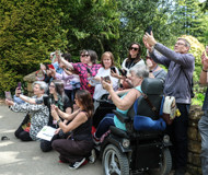 Batsford workshop participants in a big group, all taking self-portraits for one of the activities