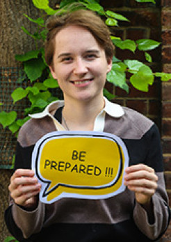 Lucy Eccles holding a speech bubble sign which says Be Prepared