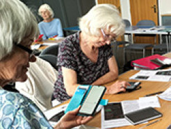 Members of the Gotherington Digital Drop-in practising with digital devices