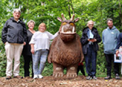Photo of a group of people in the woods next to a tall Gruffalo statue